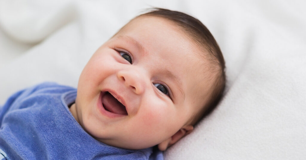 Smiling baby in a blue onesie