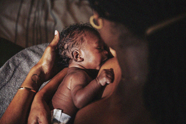An infant nursing at their parent’s chest.